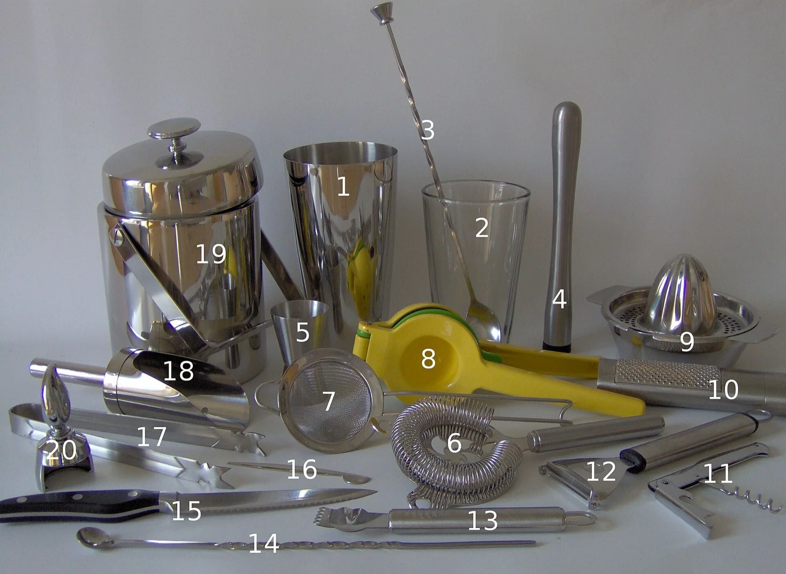 A set of home bar tools: shaker, mixing glass, jigger, strainers, bar spoon, muddler and juicer