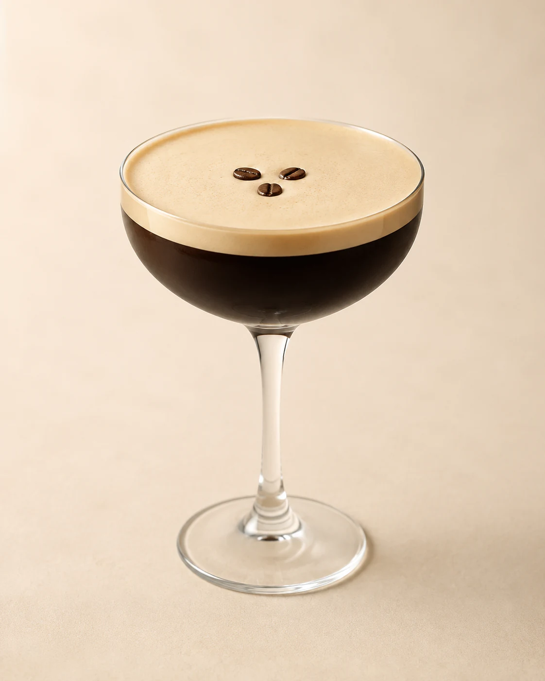 Espresso martini in a coupe glass with a thick foam top and three coffee beans